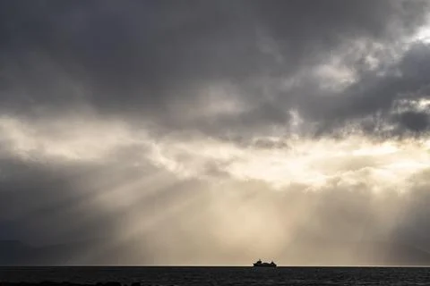 Silhouette of a ship sun rays breaking through the cloud cover Ullsfjord Lyngen Foto stock