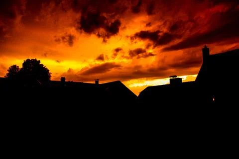 Silhouette shot of old houses in a town against a fiery evening sky in Handschuh Stock Photos