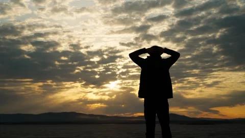 The silhouette of a single man admires the cloudy sky at sunset. Stock Footage 337565414