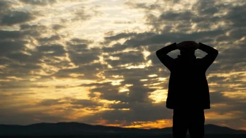 The silhouette of a single man admires the cloudy sky at sunset. Stock Footage 337565444