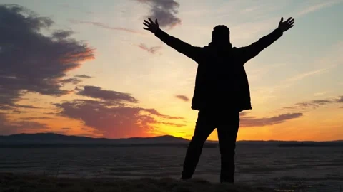 The silhouette of a single man standing on the shore of a lake at sunset. Vidéo 337563257