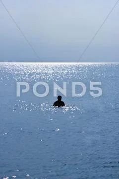 Silhouette of a Single Person Swimming on a Beach Stock Photos