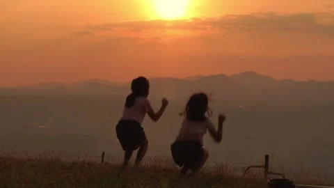 Silhouette of sisters having fun jumping outdoors in nature. Video stock 296309003
