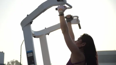 Silhouette of a slender woman on a pull-up simulator on an outdoor sports field. Stock Footage 314604425