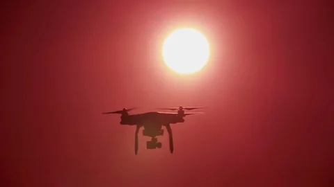 Silhouette of slow flying drone in  front of  sunset  red sky. Modern technologi Stock Footage 76485044