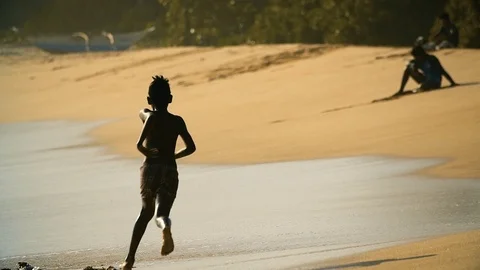 Silhouette of small boy running along sandy beach Stock Footage 85625077