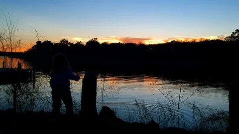 Silhouette of small child throwing rocks in lake Stock Footage 102628555