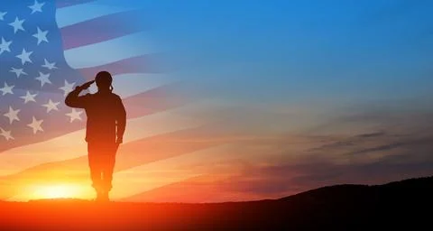 Silhouette of soldier saluting on background of sunset or sunrise and USA fla Stock Photos
