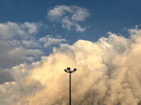 Silhouette stadium light and dramatic fluffy clouds Stock Photos