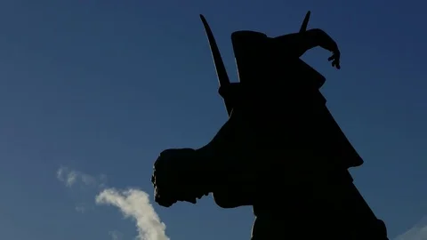 Silhouette of a statue and moving clouds/smoke in the background with a blue sky Stock Footage 75044567