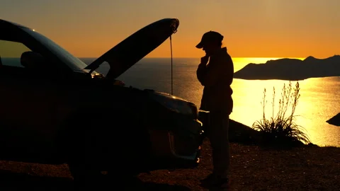 Silhouette of a stranded driver checking the car engine at sunset. Stock Footage 333209866
