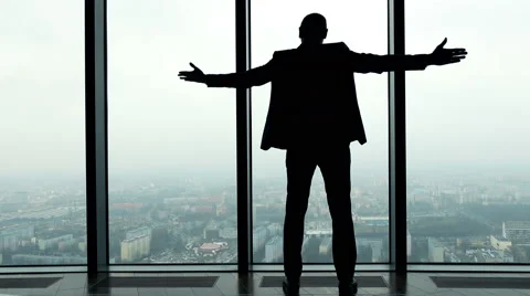 Silhouette of successful businessman raising arms, power symbol, in the office, Stock Footage