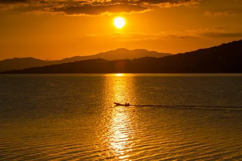 Silhouette sunset behind mountain reflection on water in dam Stock Photos