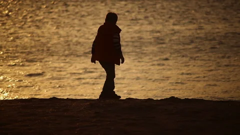 Silhouette of a sunset Boy playing with sand on the seashore by the water Video stock 150249755