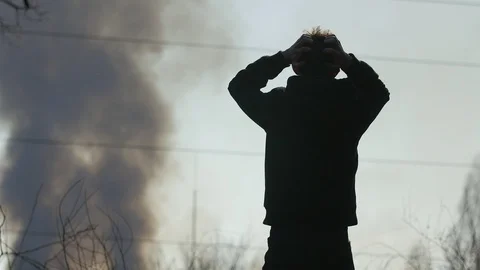 Silhouette of surprised upset boy that looking on thick black smoke from a fire Видео 105080559