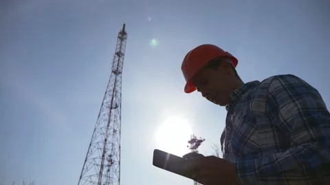 A silhouette of a telecommunications network engineer in a hard hat uses a Stockbeeldmateriaal 131294824