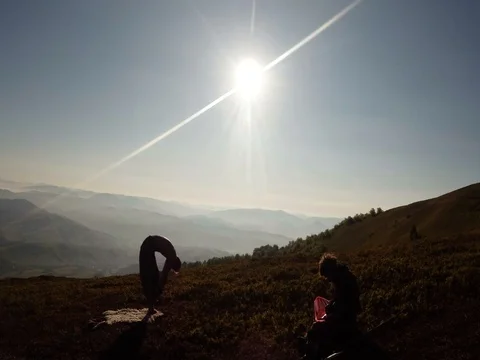 Silhouette of a thin yogi guy hands reaching out to the rays of the sun in the Stock Footage