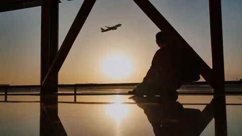 Silhouette of a tourist guy watching the take-off of the plane sitting at the Stock Footage