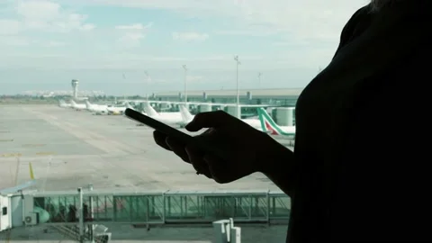 Silhouette of tourist with smartphone, using app mobile, waiting flight 스톡 동영상 166227058
