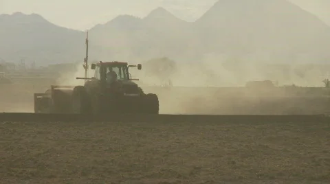 Silhouette of tractor and man walking Stock Footage