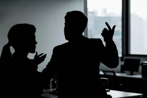 Silhouette of two business people gesturing and arguing in the office Stock Photos
