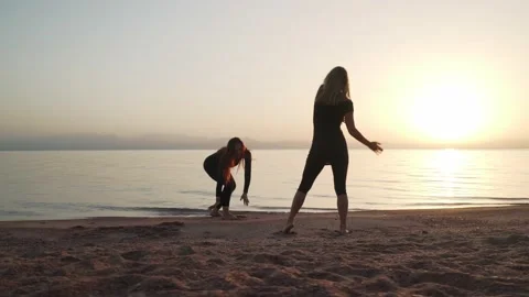 Silhouette of two female practice ecstatic dance at seashore at sunset Stock Footage 130993035