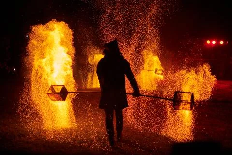 Silhouette of Two Fire Performers Creating Sparks Against Night field Stock Photos