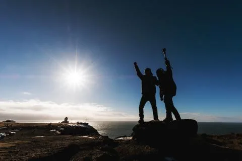 Silhouette two guy on the mountain with the sun and sun flare Stock Photos