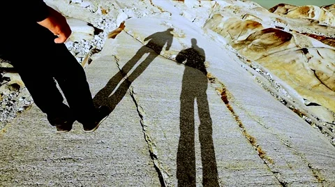 Silhouette of two hikers shadows walking on stone rocks in slow motion Stock Footage 64802444