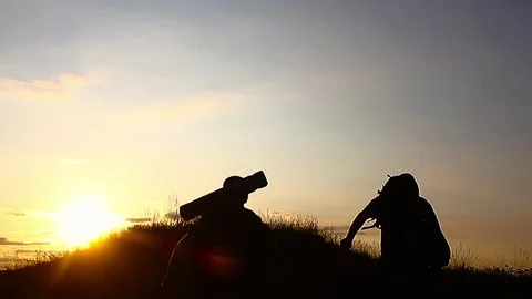 The Silhouette of two man standing on the top of mountain with Backpacks and oth Stock Footage