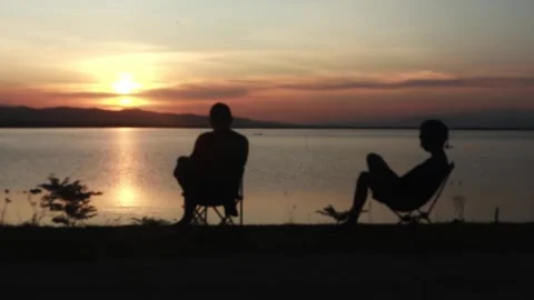 Silhouette of two men with sunset background on the lake Stock Footage 289491960
