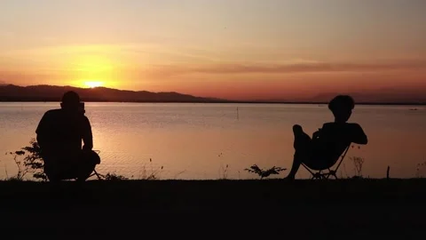 Silhouette of two men with sunset background on the lake Stock Footage 289492415