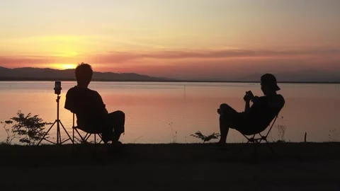 Silhouette of two men with sunset background on the lake Stock Footage 289492422