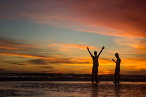 Silhouette of two people at dusk on the beach Stock Photos