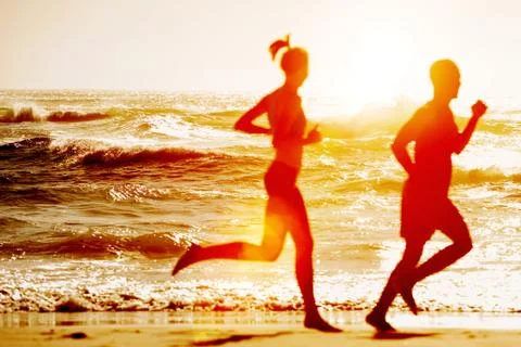 Silhouette of two running at the beach Stock Photos