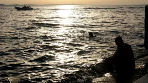 Silhouette unrecognizable man sitting on a platform stair near sea Stock Footage 90265340