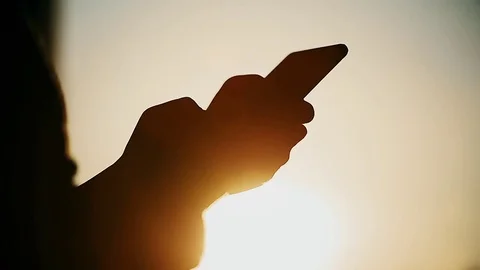 Silhouette of unrecognizable woman using a smartphone in sunset light 스톡 동영상 73094253