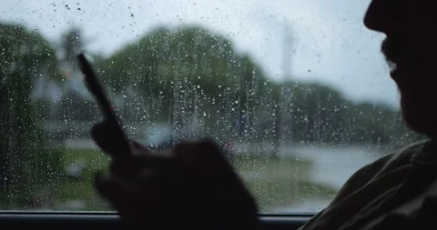 Silhouette Using Smartphone Behind Rain-Covered Window... Stock Footage 332075261