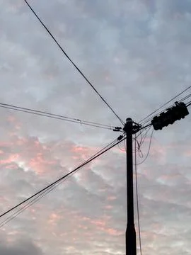 Silhouette of a Utility Pole Against Cloudy Sky Stock Photos
