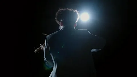 Silhouette of violinist playing under spotlight Stock Footage 335447943