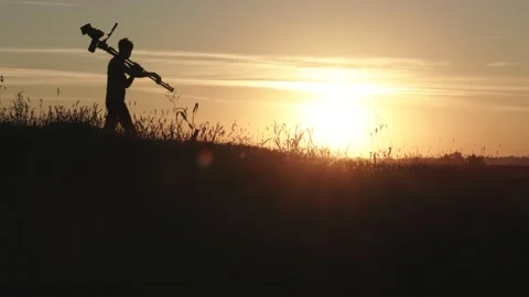 A silhouette walking with a camera pole on his shoulder Video stock 232621196