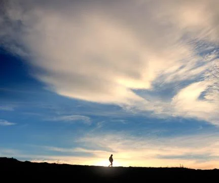Silhouette of walking traveller with backpack at the background of magnific.. Stock Photos