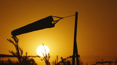 Silhouette of wind sock at sunset sky. Wind sock in countryside at sunset. Wind Stock Footage 245981308