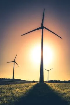 Silhouette of wind turbines on the fields in the light of the rising sun Stock Photos