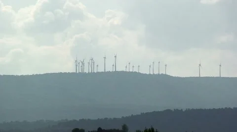 Silhouette of windmill farm on a hill, clouds in the sky Stock Footage 50078692