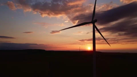 Silhouette of windmill turbine in field at sunset sky. Rotating wind generator Stock Footage