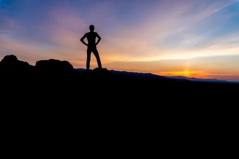 Silhouette of a winner man standing on a mountain. Stock Photos