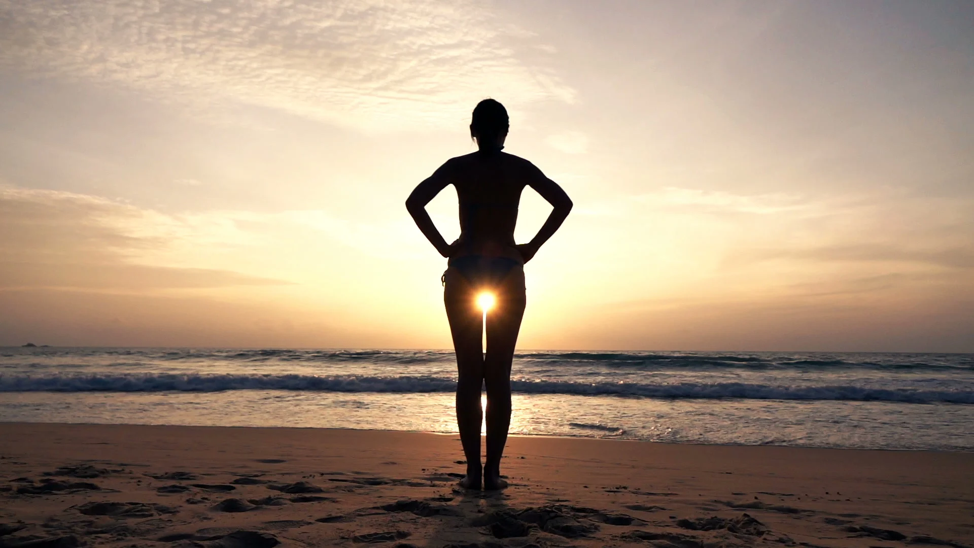 Silhouette of woman in bikini standing on beach during sunset super slow motion