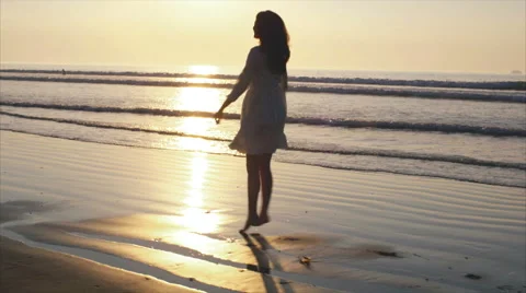 Silhouette of woman dancing and spinning on wet sea shore at sunset Stock Footage 59062308