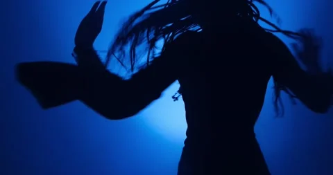 Silhouette of woman dancing in blue light and smoke Stock Footage